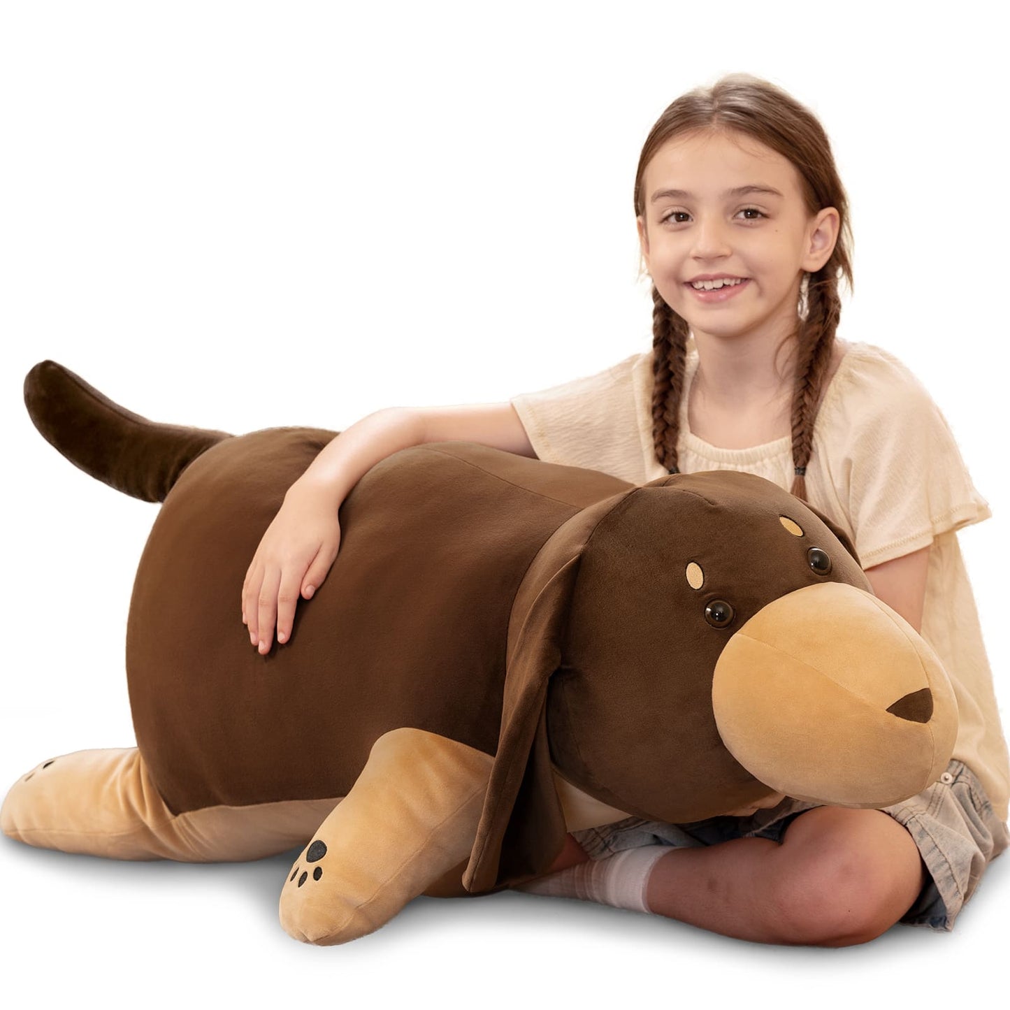Child with a large brown dog-shaped pillow on a white background